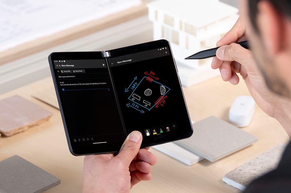 Die Hand einer Person hält Surface Duo 2 for Business in der einen und einen Surface Pen in der anderen Hand.