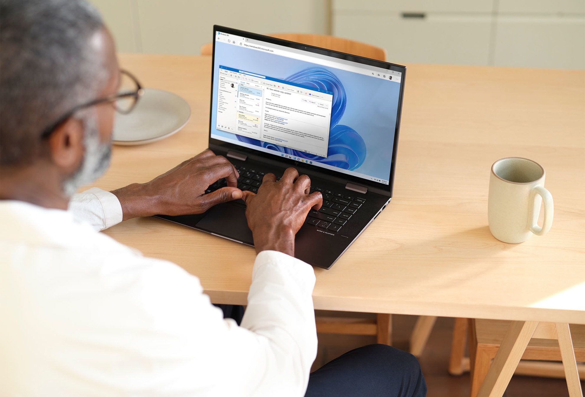 A person using Outlook on a laptop at a kitchen table.