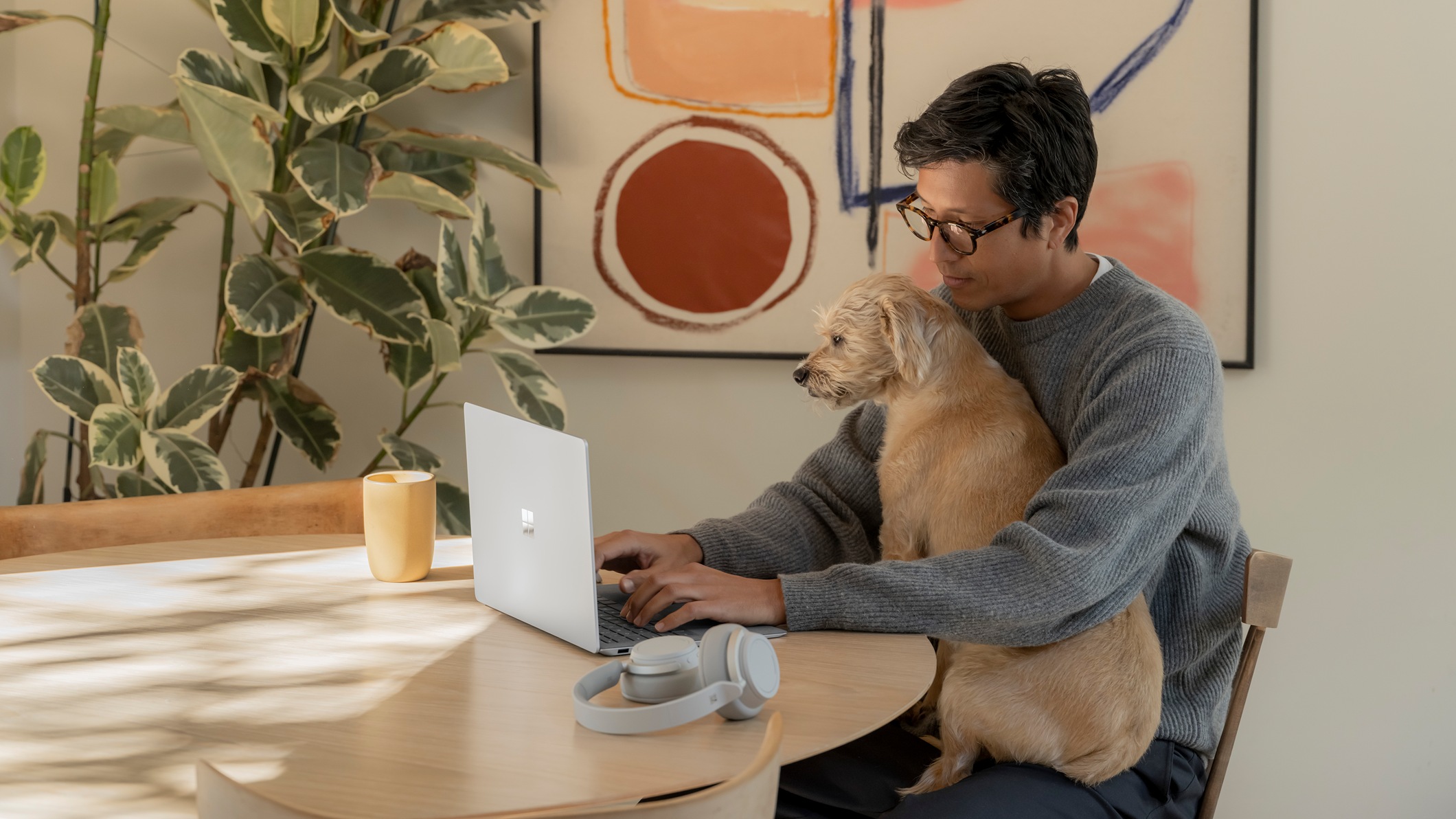 Yanında köpeğiyle evde çalışırken dizüstü bilgisayarında yazı yazan adam.