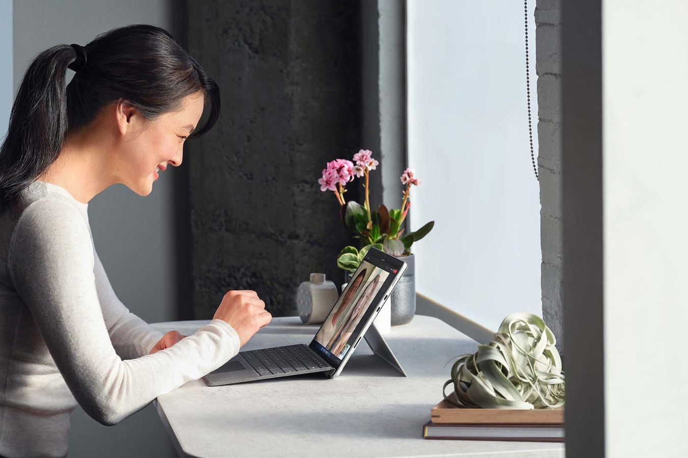 Se observa una persona, en un entorno de trabajo remoto, aceptando una llamada de Microsoft Teams desde un dispositivo Surface Pro 8