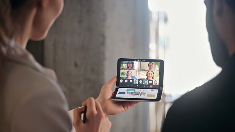 A person holding a Surface Duo 2 in Compose Mode while in a Teams meeting