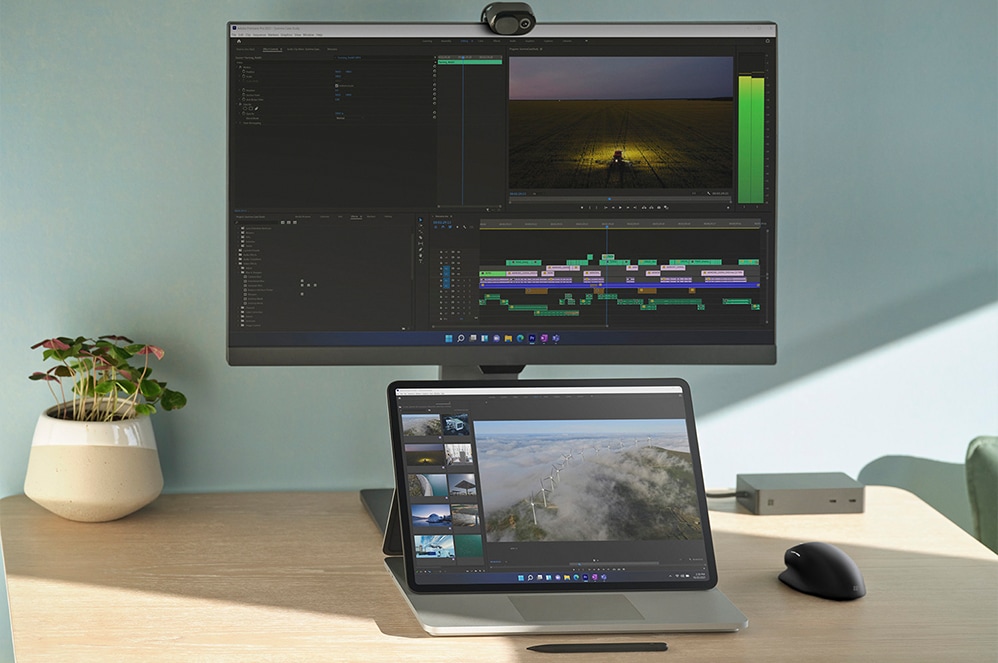 외부 모니터에 연결되어 사무실 책상 위에 놓인 도킹 모드의 Surface Laptop Studio. 앞에는 Surface 슬림 펜 2가 놓여 있습니다.