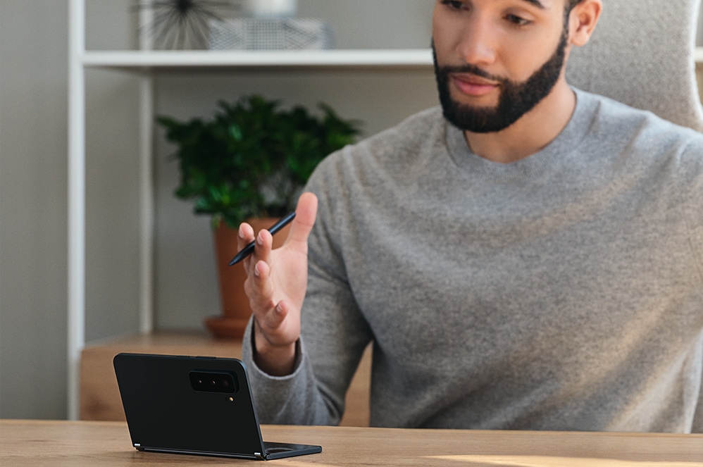 Eine Person sitzt an einem Tisch, auf dem Surface Duo 2 liegt.