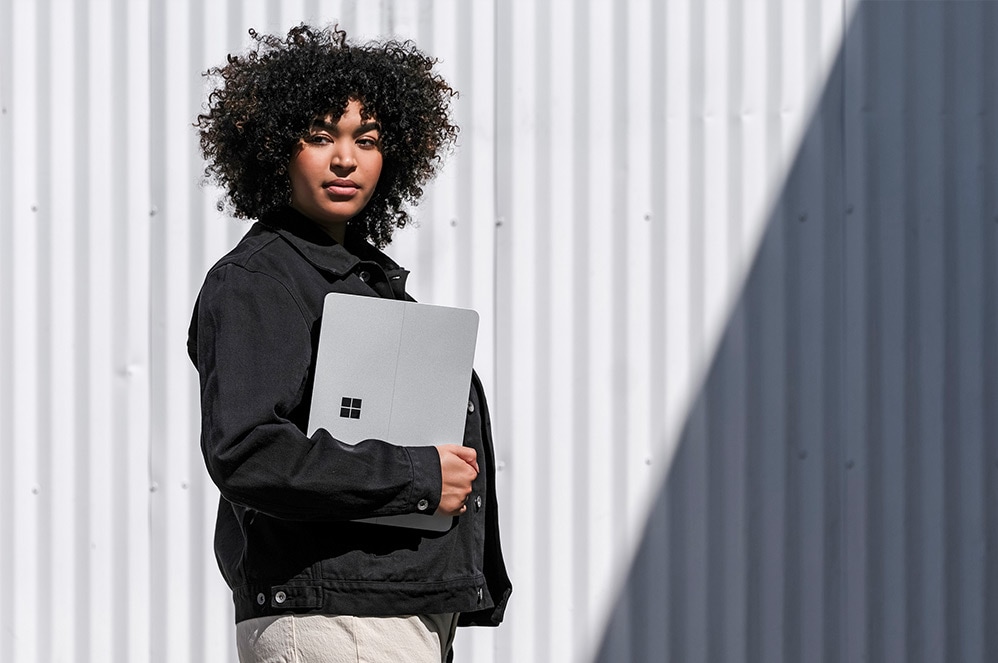 A person stands outside with Surface Laptop Studio.