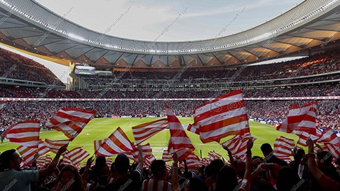 Un stade de soccer avec des supporters tenant des drapeaux rayés rouges et blancs.