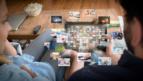 Twee mensen kijken naar een tablet met verschillende video’s en apps.