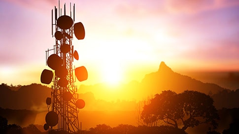 Une grande structure de télécommunications devant un coucher de soleil coloré.