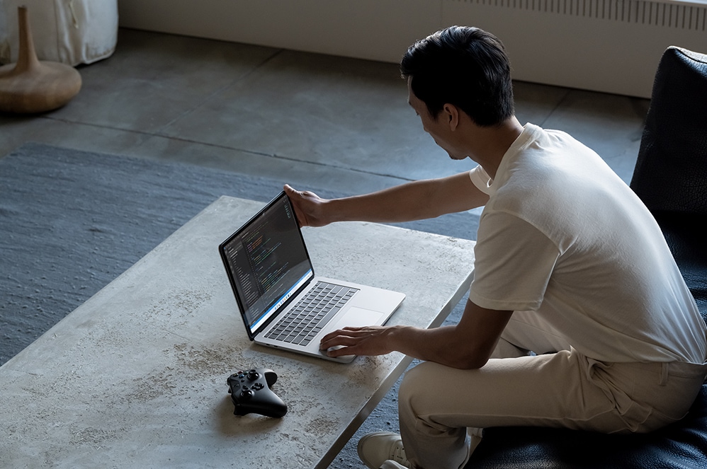 คนคนหนึ่งใช้ Surface Laptop Studio ในโหมดแล็ปท็อปเขียนโค้ดอยู่ในห้องนั่งเล่น
