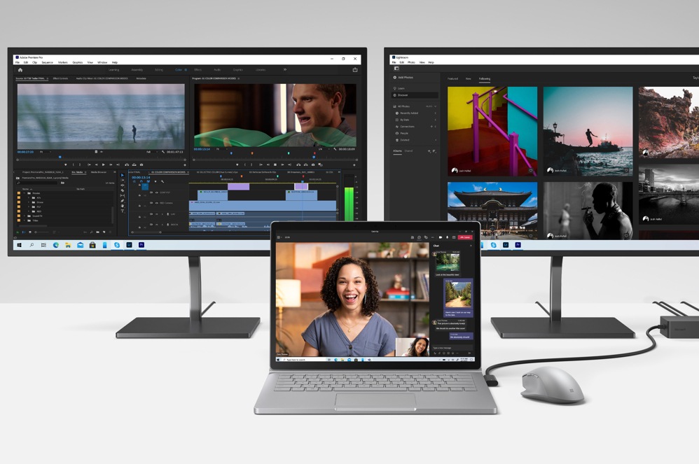 Dva monitory s aplikacemi Adobe, v popředí je zařízení Book 3 s myší pro Surface Mouse a dokovací stanicí