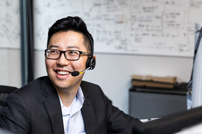 A customer service representative wearing a headset and smiling.