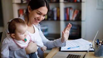 Vanhempi ja vauva osallistumassa virtuaalitapaamiseen kannettavalla tietokoneella.