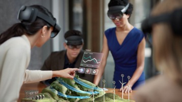 Three people using HoloLens 2 to view city models in augmented reality.