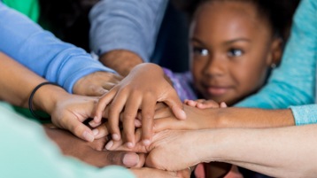 Children and adults stacking hands.