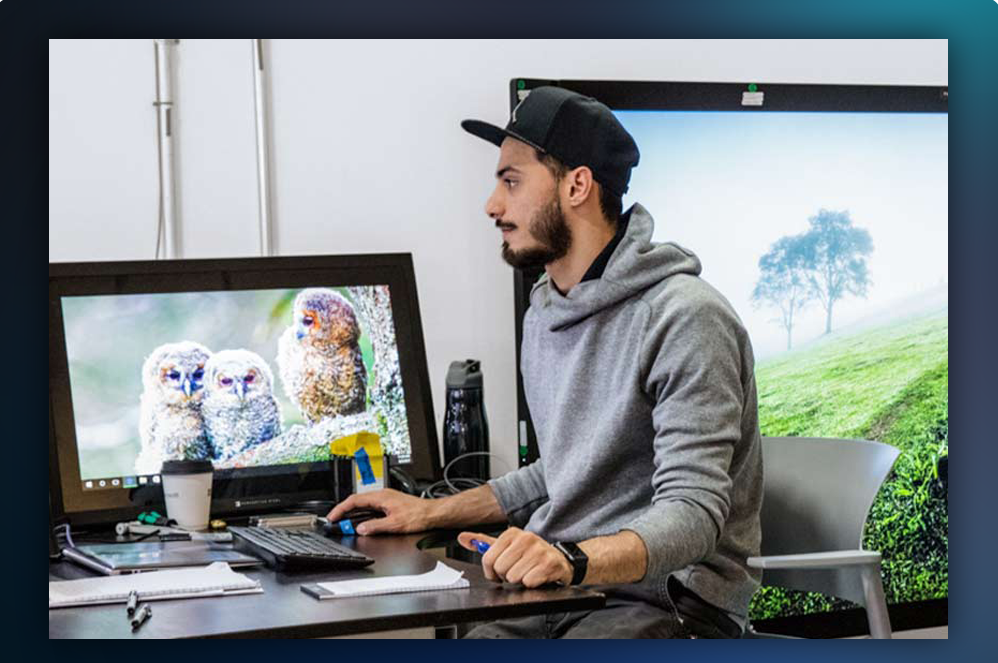 Mężczyzna pracujący przy biurku z dwoma monitorami komputerowymi