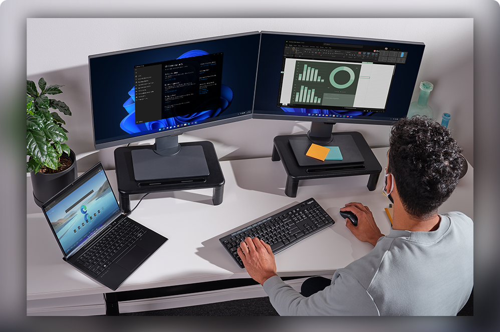 Mężczyzna przy stanowisku pracy z dwoma monitorami komputerowymi i laptopem