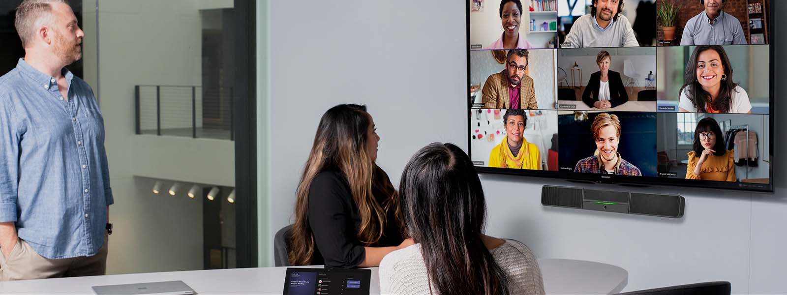 Três pessoas em uma sala de conferência participando de uma videoconferência