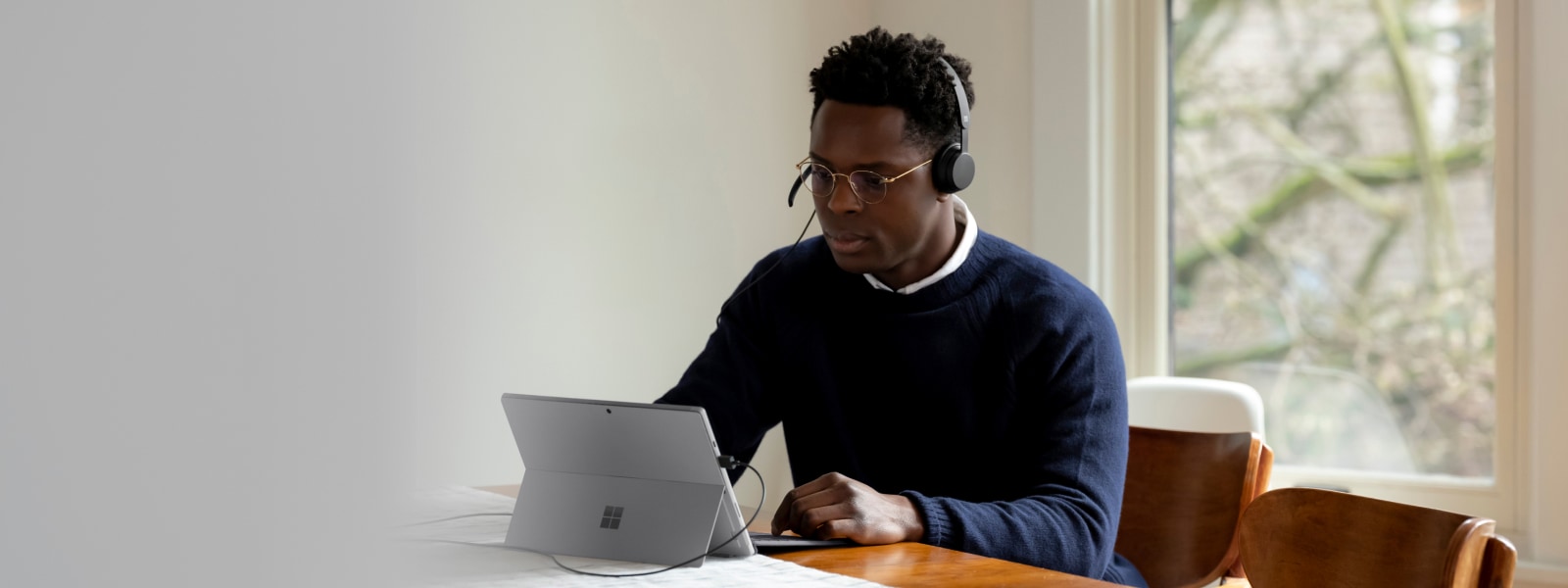 Volwassene die binnen zit met een Surface Pro en een Microsoft Modern USB-headset