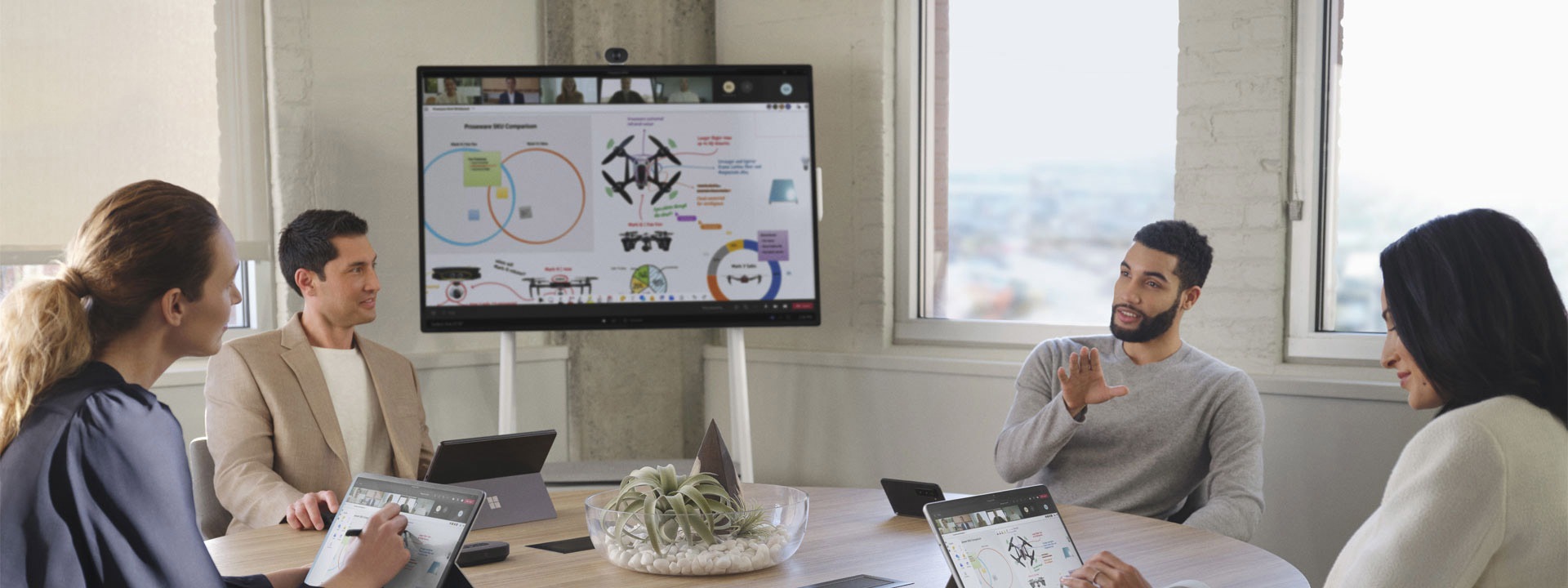 Neljä työtoveria neuvotteluhuoneessa pitämässä Microsoft Teams -kokousta erilaisten Surface-laitteiden kanssa