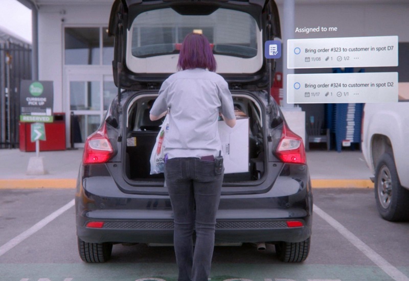 A person loading items into the trunk of a car and tasks are being assigned to them in Teams. 