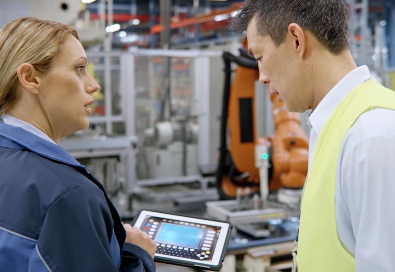 Two people in a warehouse looking at a tablet device. 
