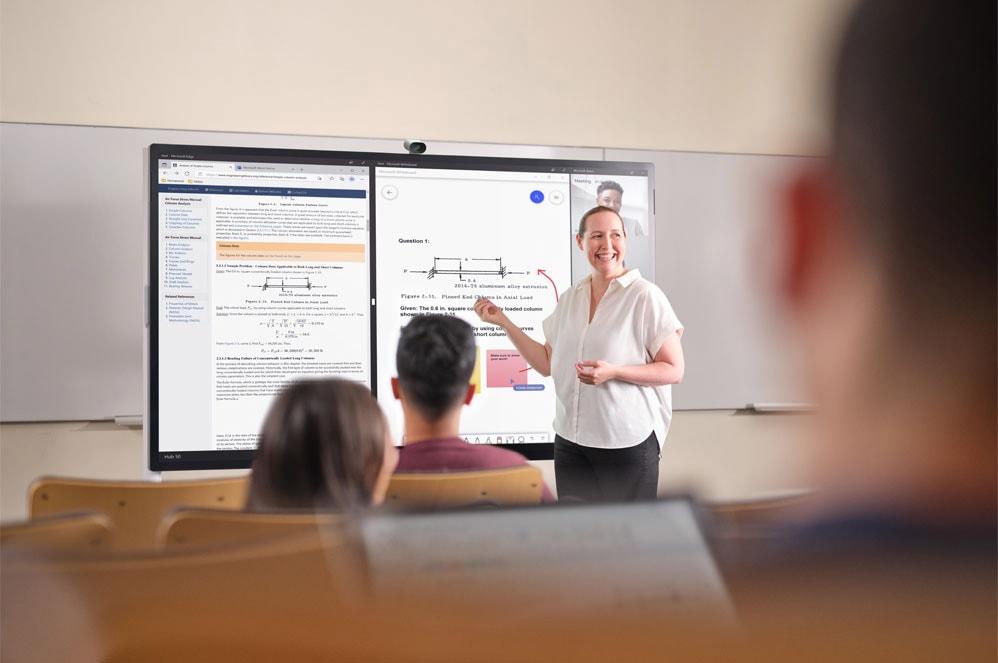 A teacher standing in front of Surface Hub 2S lectures to a class
