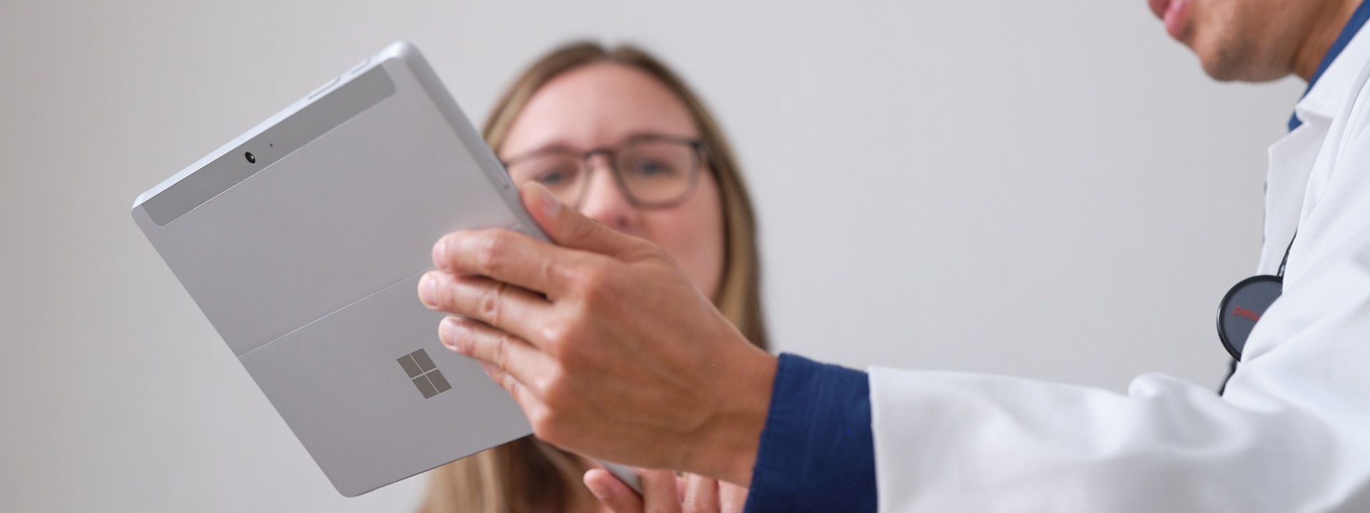 Lékař ukazuje pacientovi léčebný plán na zařízení Surface Pro