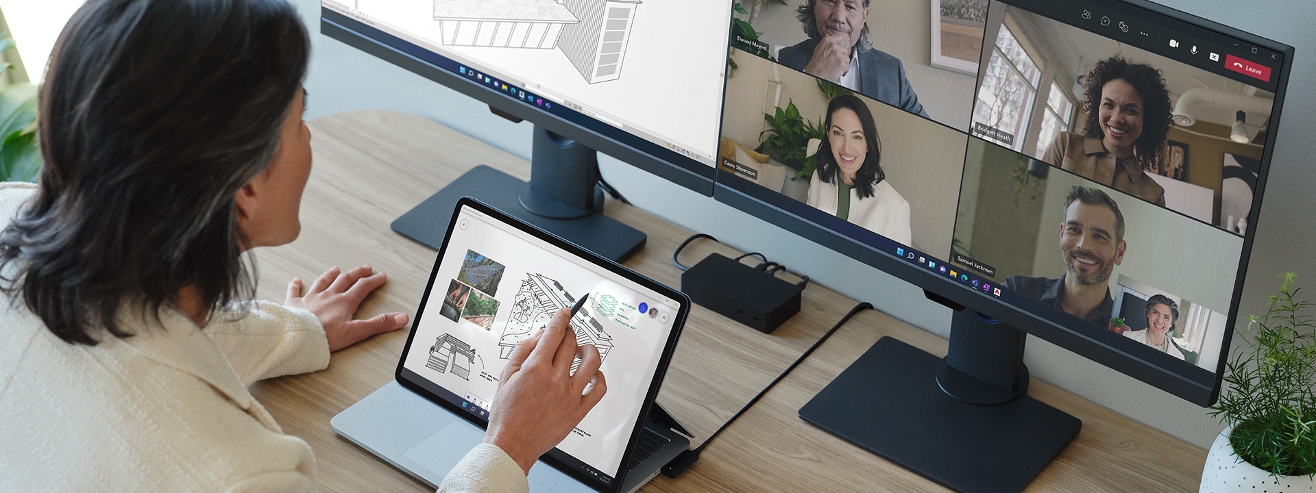 En person samhandler med skjermen på en Surface Laptop Studio som er koblet til to eksterne skjermer