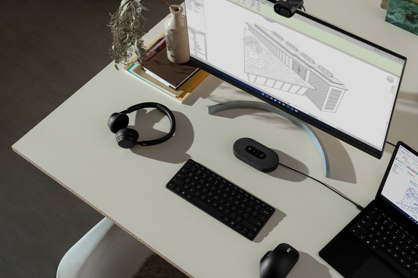 A Surface device is seen sitting on a desk connected to an external monitor with various Surface accessories nearby