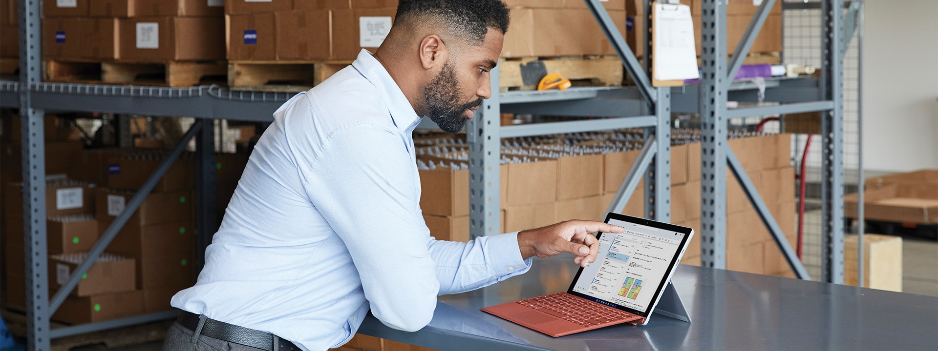 Varastossa oleva mies Microsoft Teams -videopuhelussa. Käytetty laite on kannettavan tietokoneen tilassa oleva platinanvärinen Surface Pro 7+.