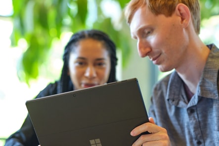 Two people collaborate while looking at a Surface device