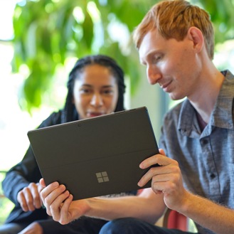 Two people collaborate while looking at a Surface device