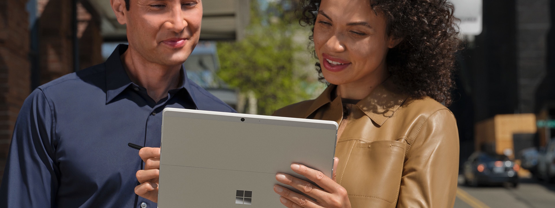 Zwei Kollegen arbeiten über ein Surface Go 3 zusammen in einer großstädtischen Umgebung
