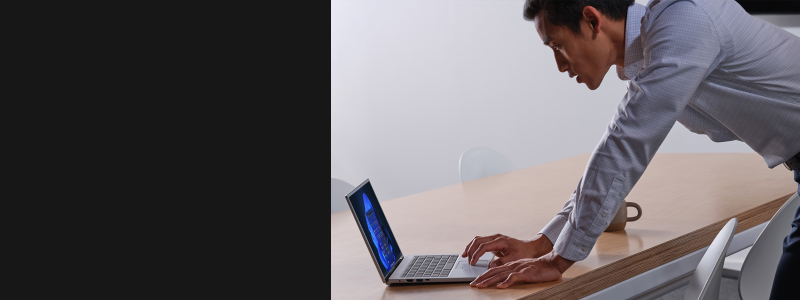 A man leaning over a table while  using a laptop