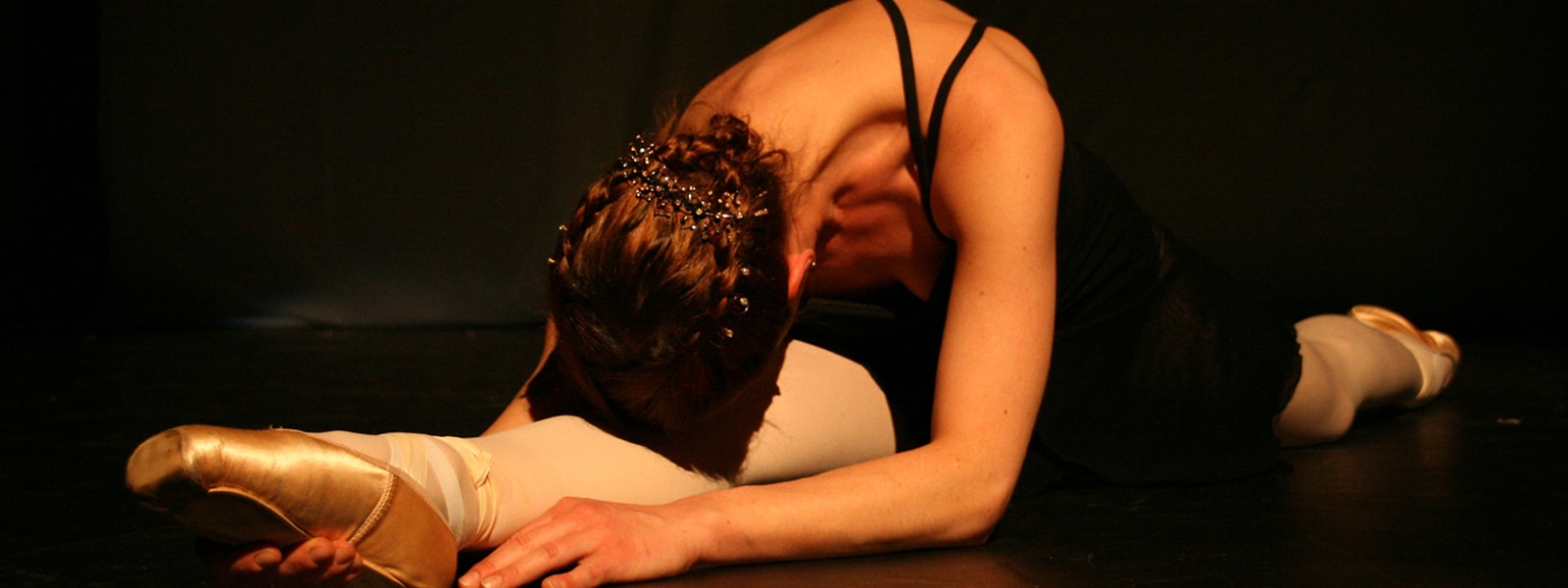 Das Bild zeigt eine Ballett-Tänzerin bei einem Spagat.