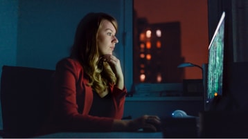 Osoba, která se dívá na data zobrazená na monitoru stolního počítače. 