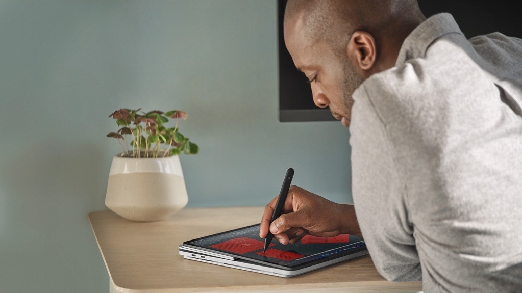 A person sitting at a desk uses a Surface Slim Pen 2 to mark up a document on Surface Laptop Studio