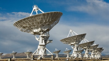 Large radio astronomy antennas in a field.
