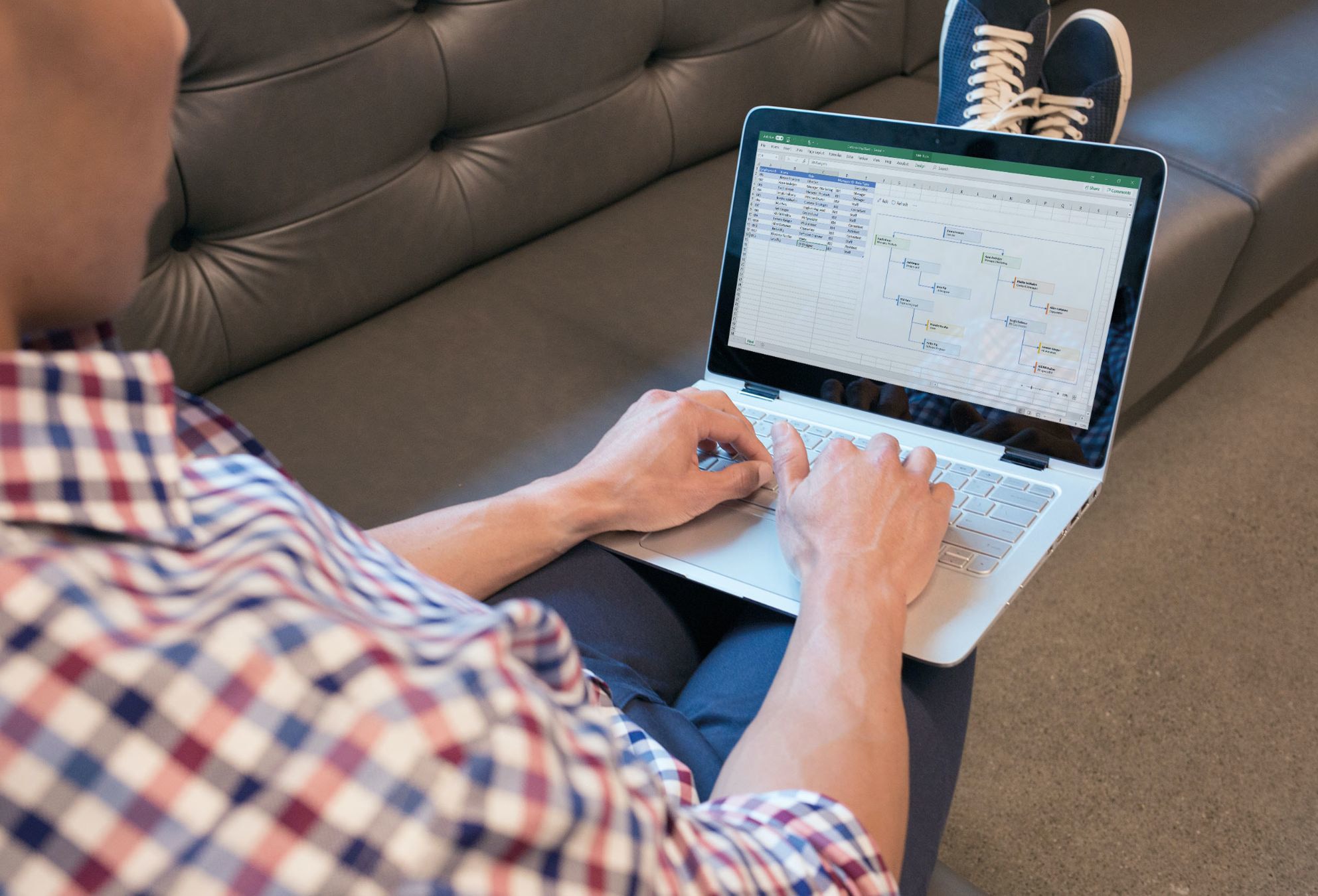 אדם שיושב על ספה באמצעות מחשב נייד כדי לערוך גיליון אלקטרוני ב- Excel