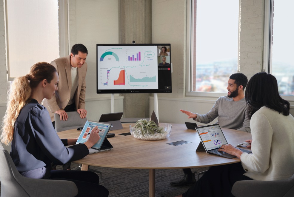 Team aus vier Mitgliedern, die in einem Konferenzraum mit einem Surface Hub 25 50-inch arbeiten.
