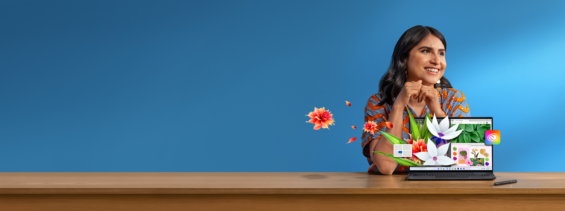Une femme en robe rayée est assise à un bureau, un ordinateur portable devant elle. Des éléments digitaux tels que des grilles Snap et des illustrations florales Photoshop apparaissent comme par magie sur l’écran.