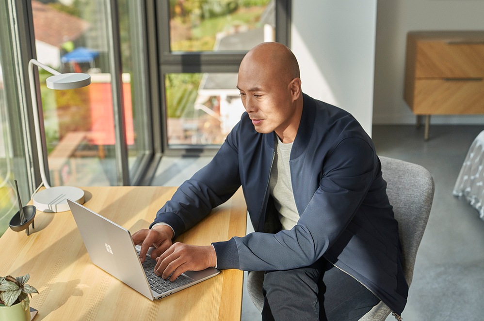 A person seated at a desk uses Surface Laptop Go 2 for Business.