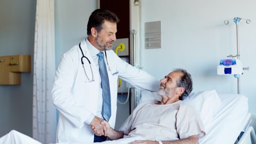 一位医生在与一名卧床患者握手。
