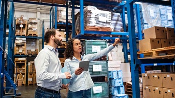 Two people in a warehouse looking at inventory.