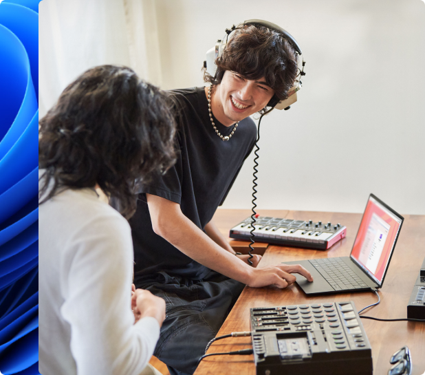 ヘッドホンを着用している笑顔の若い男性と、電子キーボードを使ってノート PC で作曲中の別の人物。