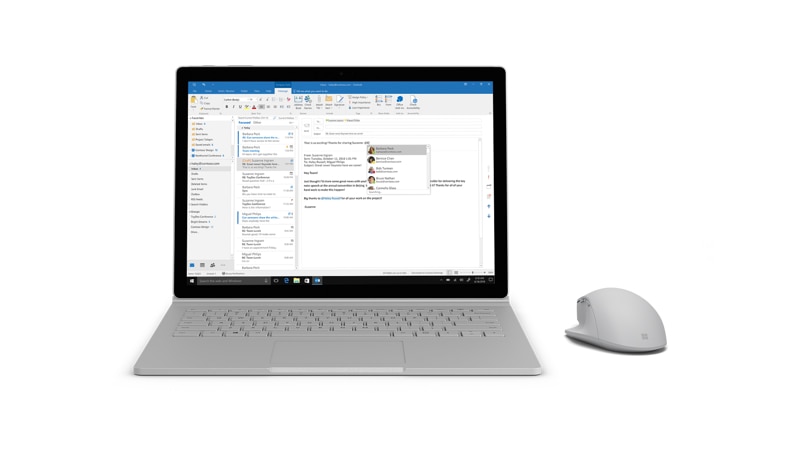 Surface Precision Mouse next to a Surface Book 2 running Outlook
