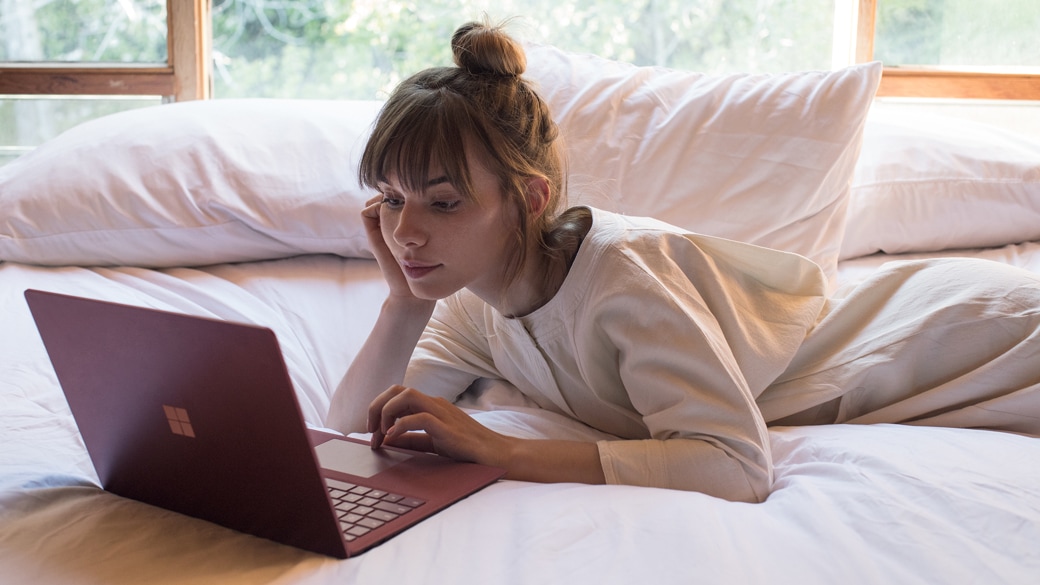 A person using a Surface Laptop in bed