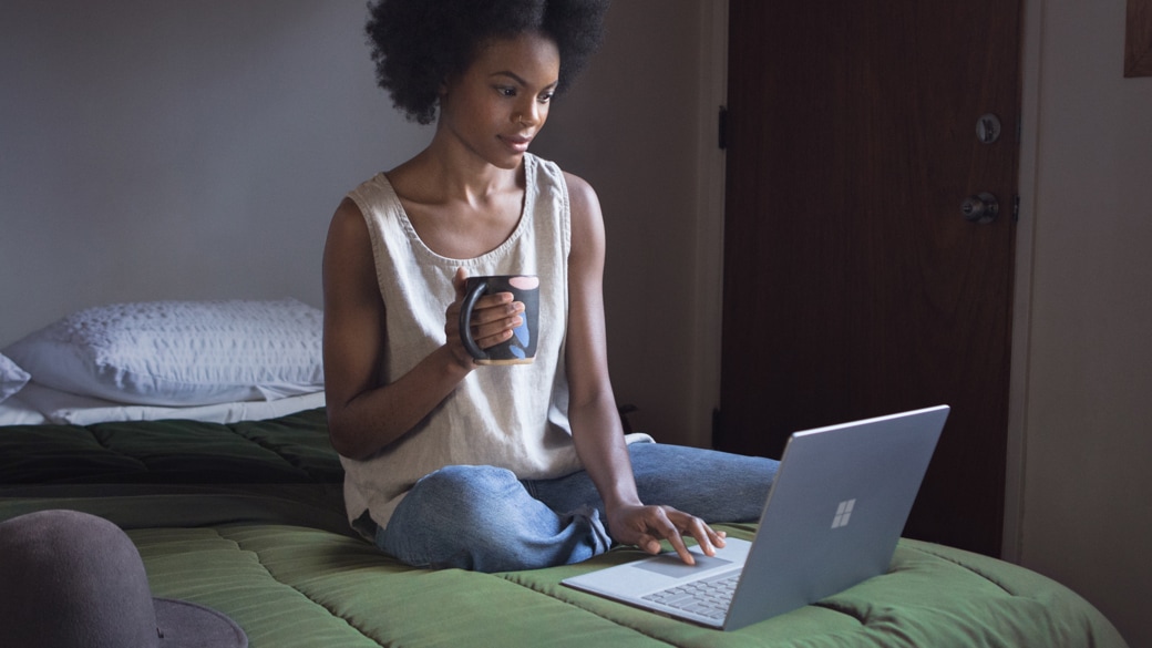 A person having using a Surface Laptop in bed