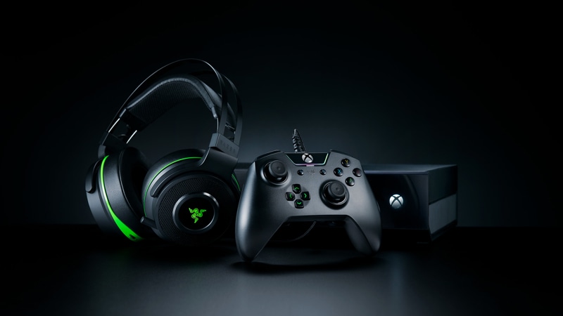 Razer Wolverine Tournament Edition Gaming Controller for Xbox One beside Razer headphones, in front of the Xbox One console