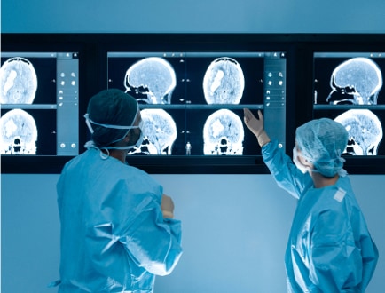 Zwei medizinische Fachkräfte, die auf einen Bildschirm mit Gehirnscans blicken 