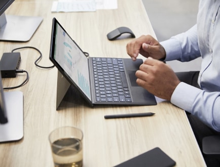 一个人在办公桌前使用连有键盘的平板电脑。